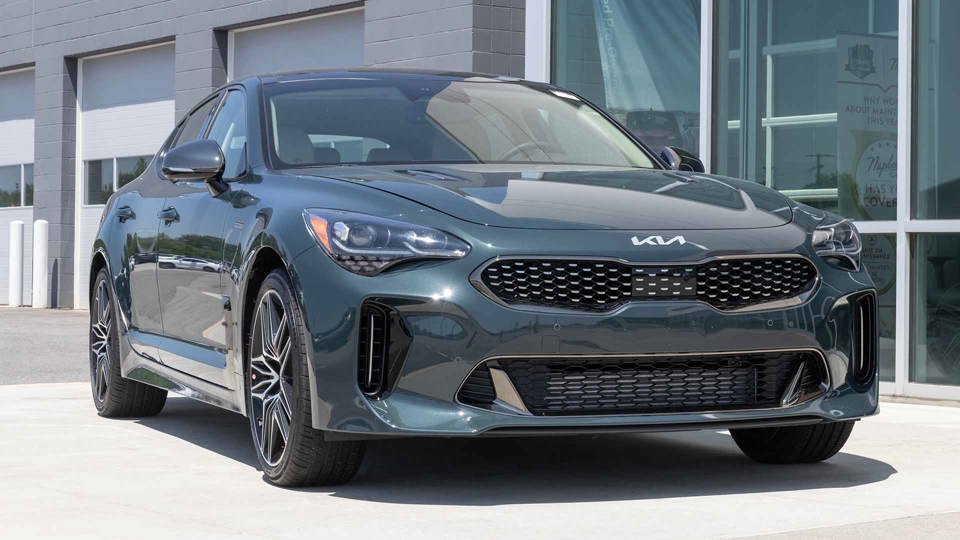 Grey-green Kia Stinger parked outside car garage