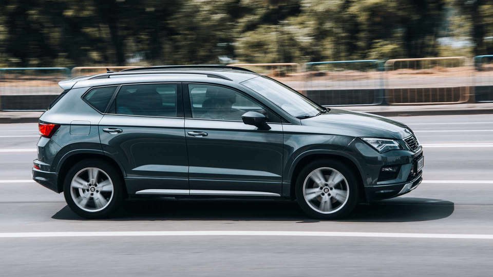 Grey SEAT Ateca driving along road with barriers