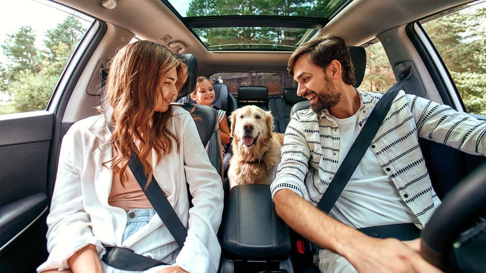 Family in a  with a dog in the middle of the back seat