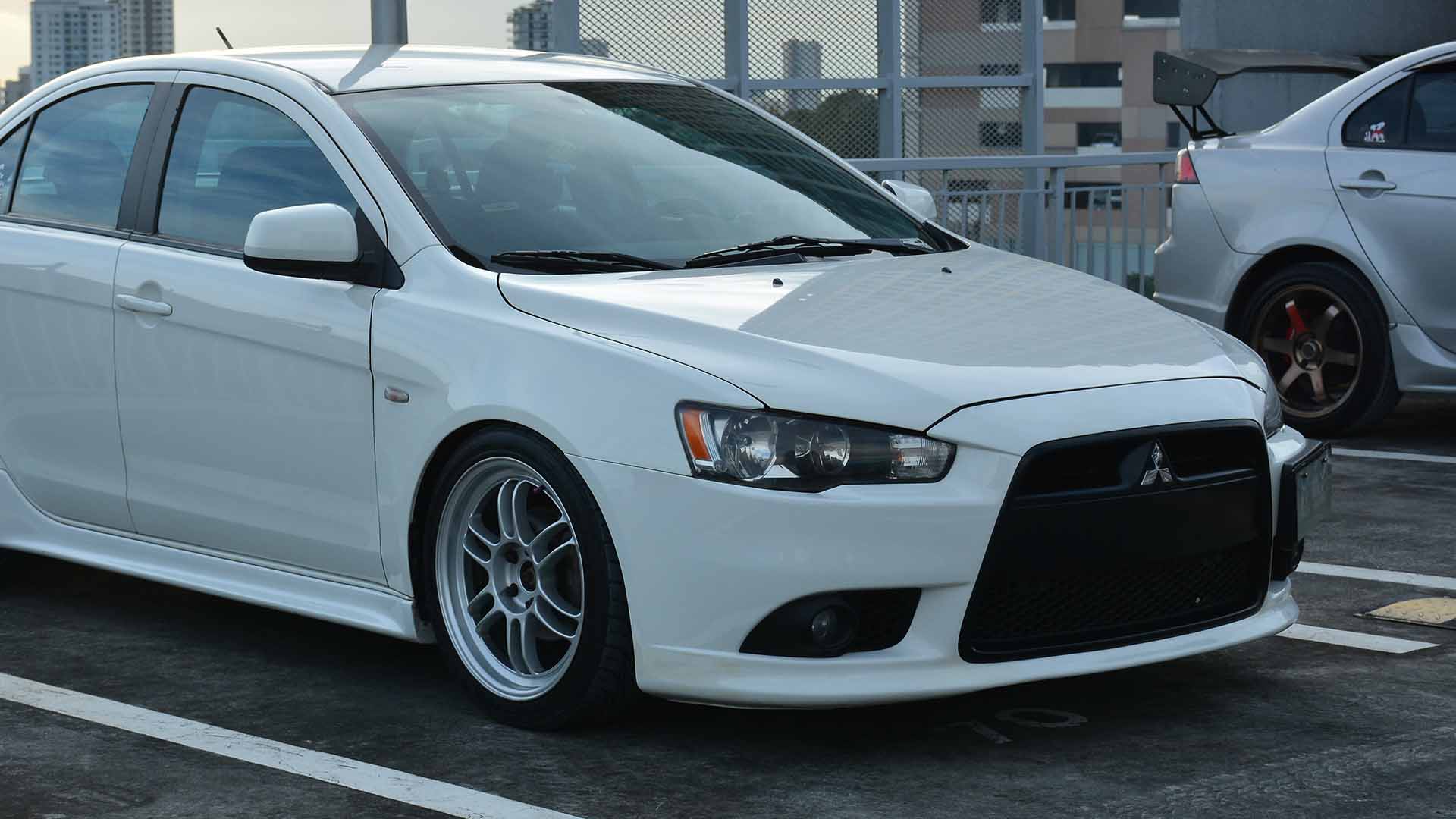 White Mitsubishi Lancer parked in car park on a roof