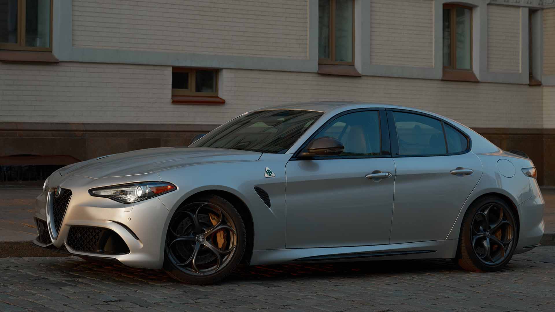Grey Alfa Romeo Giulia parked on road outside a white brick building