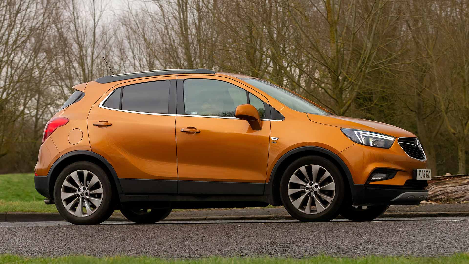 Orange Vauxhall Mokka X at a park with trees in the background