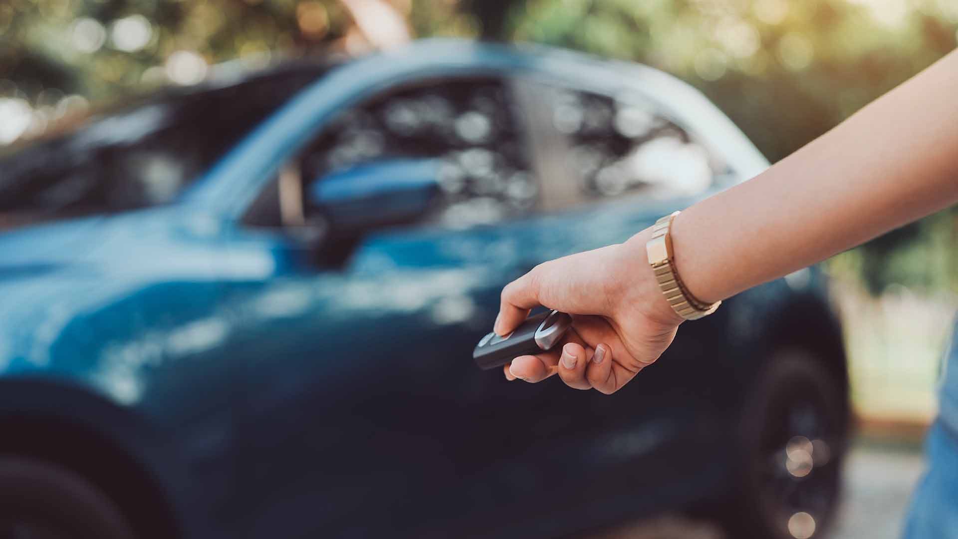 Blue car and car key in persons hand